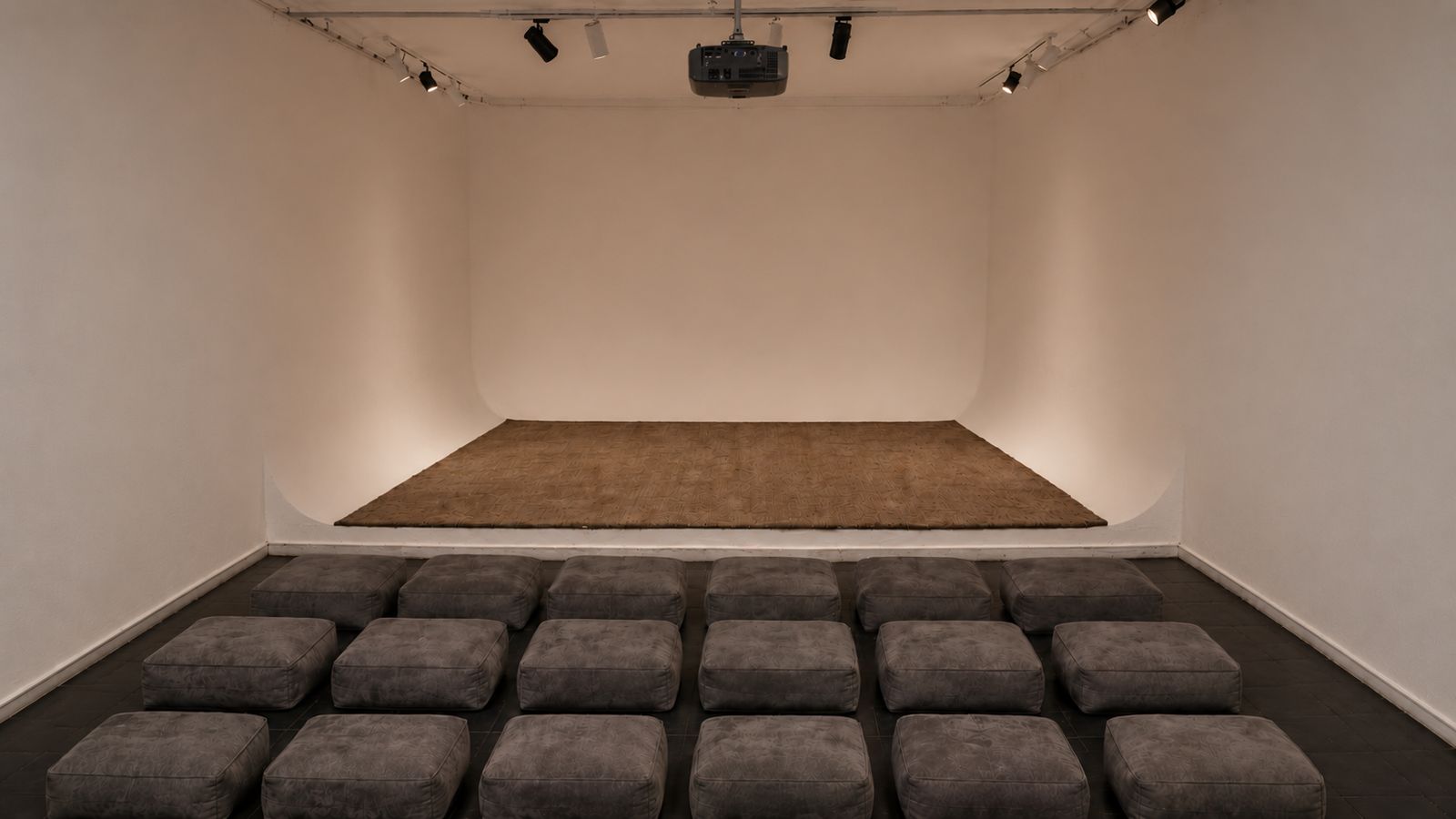 Sinema Siri cinema room — rows of grey cushions facing the stage under warm light